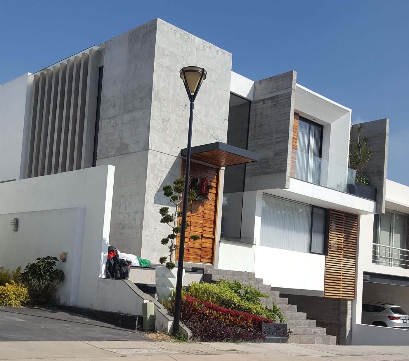 Fachada residencial en concreto con puerta de madera, proyecto Arq. Eduardo Espinosa